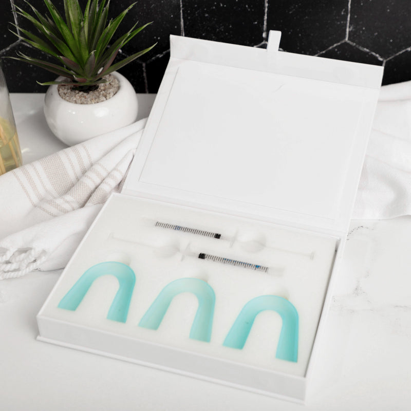 The inside of a CustMbite Smile Whitening Kit, which includes 2 application syringes and 3 trays.